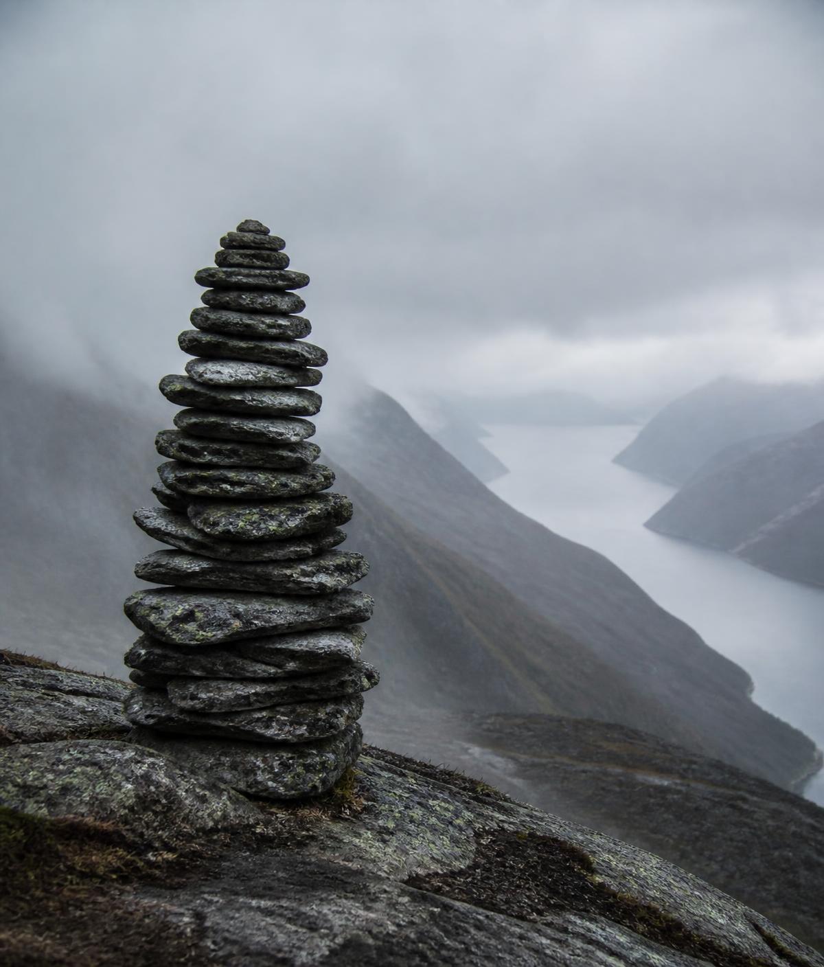Stone cairn on a rocky ridgeline with cold Nordic mountains behind it