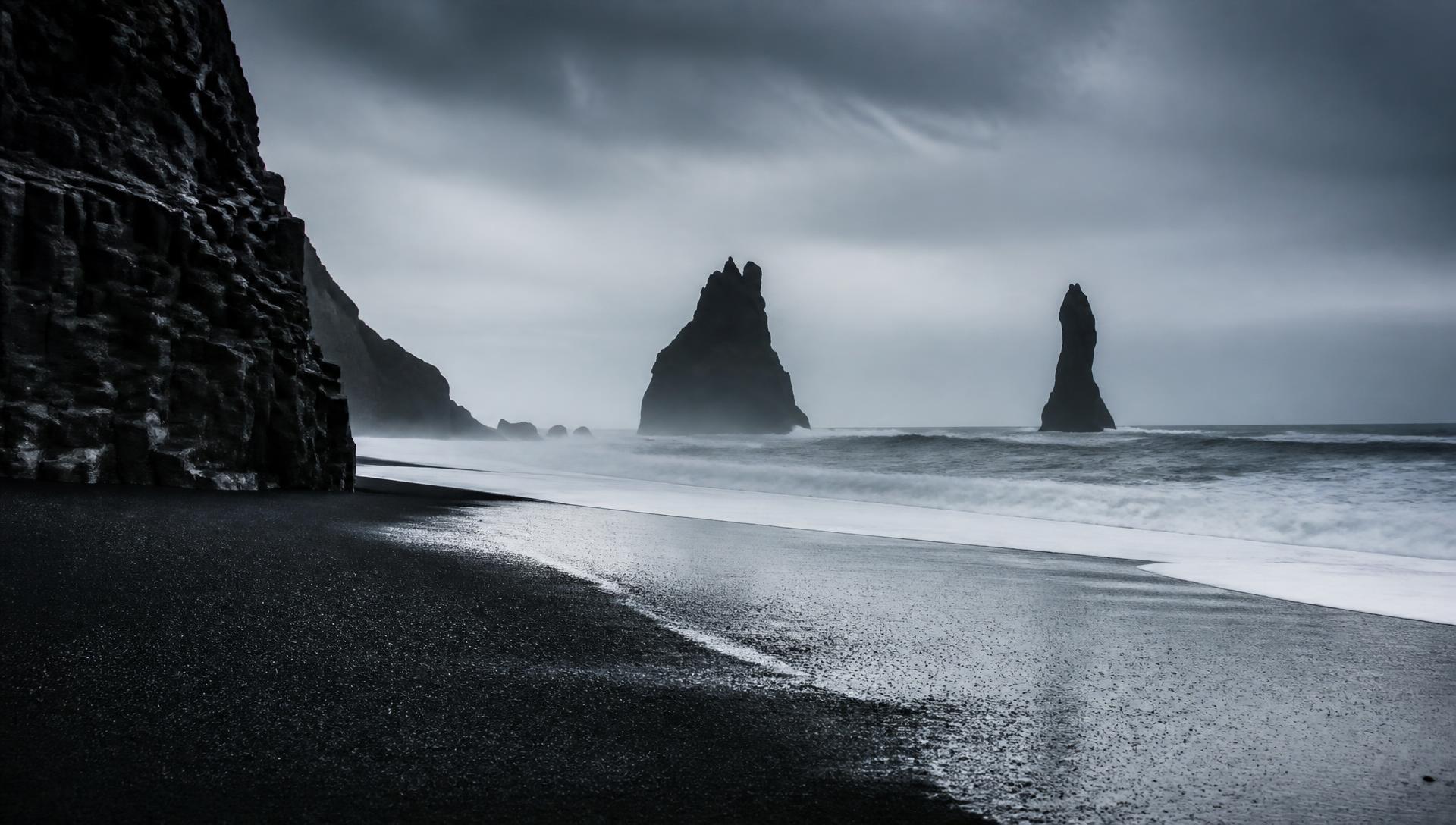 Black sand beach and basalt sea stacks under cold Icelandic light